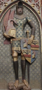 Платинчатые набедренники, латные поножи, чешуйчатые сабаттоны, шлем басинэ с забралом, закрепленным на налобном шкворне, топфхельм с геральдической фигурой. Надгробие Рудольфа фон Заксенхаузена